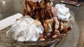 black and tan chocolate and toasted almond ice cream with fudge and caramel sauces side-by-side in a sundae dish
