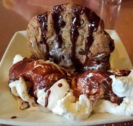 vacation ice cream sundae with a hot chocolate chip cookie covered in hot fudge