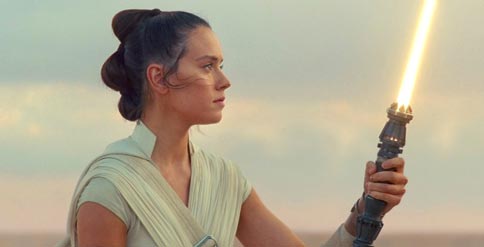 Star Wars character Rey holds her yellow light saber