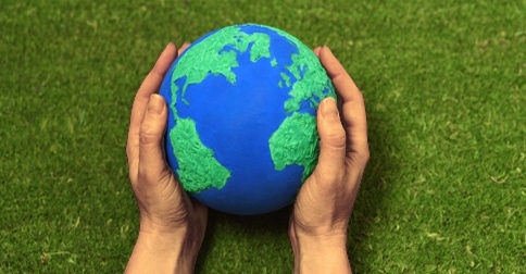 brown hands holding model of planet earth
