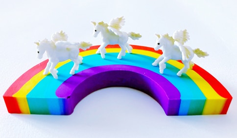 3 white unicorns on a rainbow