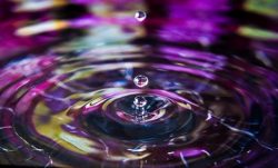 water droplet slow motion onto purple tinted water