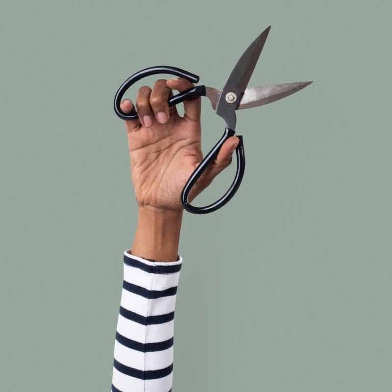 upraised hand holds antique scissors ready to cut, cut, cut