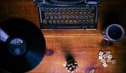 wood desk with typewriter vinyl record scrabble tiles paint and music