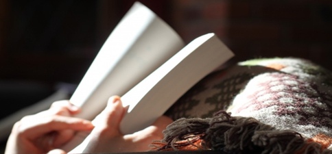 woman reading with cozy blankets