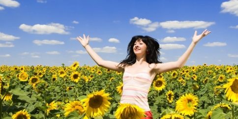 woman triumphant in field of sunflowers